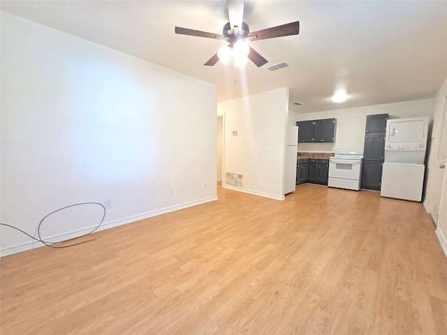 201 Paschal, Troup, TX 75789 - unfurnished living room with stacked washing machine and dryer, a ceiling fan, baseboards, and light wood-style floors