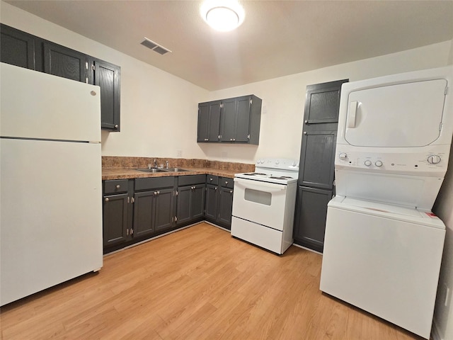 201 Paschal, Troup, TX 75789 - kitchen with white appliances, stacked washer / drying machine, a sink, light wood finished floors, and dark countertops
