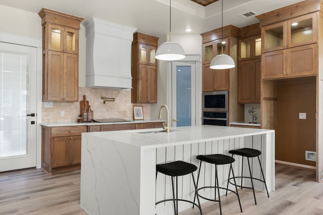 1228 Gould Ave, Fort Worth, TX 76164 - kitchen featuring wall chimney exhaust hood, a sink, stainless steel appliances, brown cabinets, and light wood finished floors