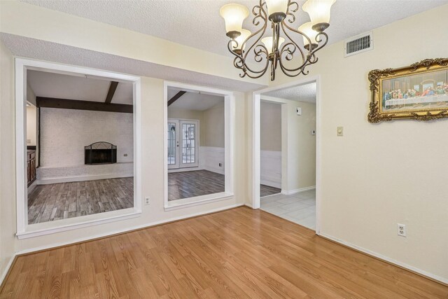 2622 Briar Hill Dr, Carrollton, TX 75007 - unfurnished dining area featuring a chandelier, wood finished floors, a large fireplace, a textured ceiling, and baseboards