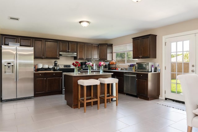 2300 Ash Grove Trl, Fort Worth, TX 76112 - kitchen with appliances with stainless steel finishes, under cabinet range hood, dark brown cabinets, and a breakfast bar
