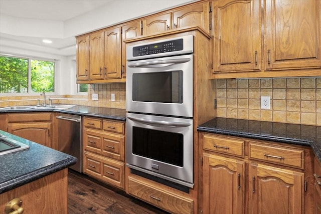 3519 Lake Powell Dr, Arlington, TX 76016 - kitchen featuring appliances with stainless steel finishes, a sink, dark wood-style floors, brown cabinets, and backsplash