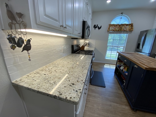 2900 Boyd St, Ennis, TX 75119 - kitchen with stainless steel appliances, wood counters, wood finished floors, tasteful backsplash, and white cabinetry