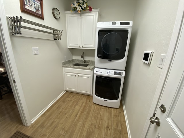 2900 Boyd St, Ennis, TX 75119 - laundry room featuring stacked washer / dryer, cabinet space, light wood finished floors, and baseboards