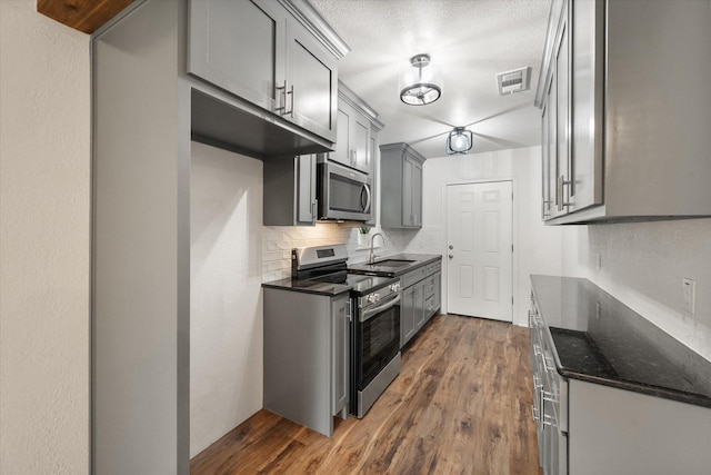 1111 N 11th St, Waco, TX 76707 - kitchen with appliances with stainless steel finishes, dark wood-type flooring, tasteful backsplash, and a sink