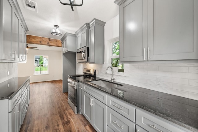 1111 N 11th St, Waco, TX 76707 - kitchen with stainless steel appliances, a sink, gray cabinets, a ceiling fan, and backsplash