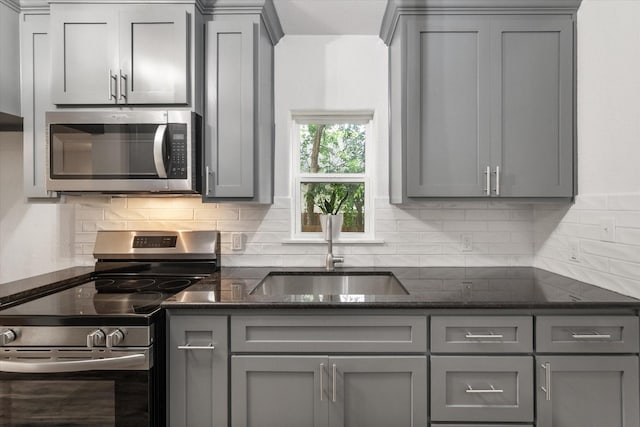 1111 N 11th St, Waco, TX 76707 - kitchen featuring stainless steel appliances, gray cabinetry, a sink, backsplash, and dark stone counters