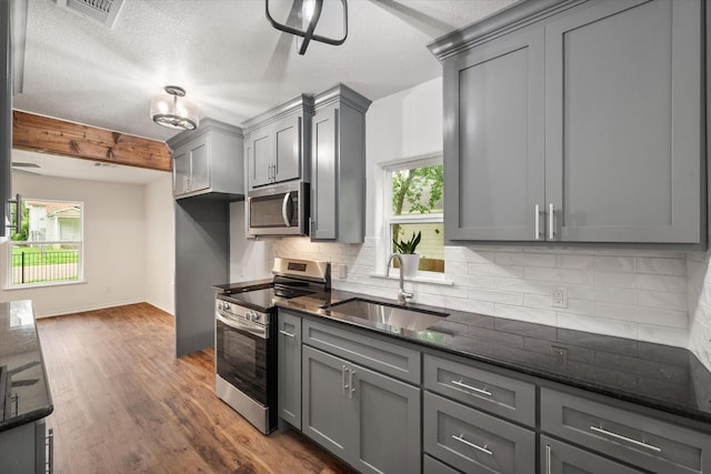 1111 N 11th St, Waco, TX 76707 - kitchen featuring stainless steel appliances, a sink, gray cabinetry, dark stone counters, and beamed ceiling