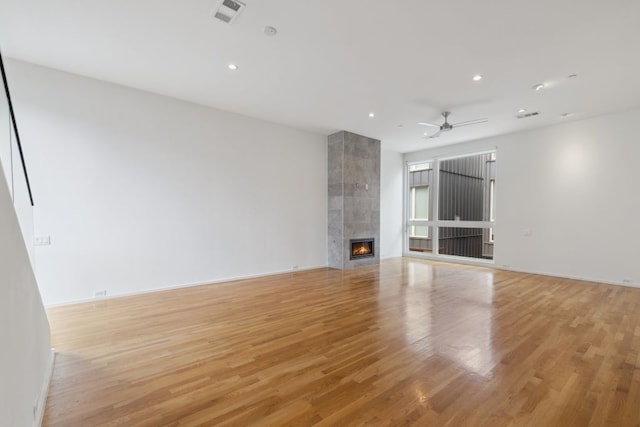 2706 Throckmorton St Unit C, Dallas, TX 75219 - unfurnished living room featuring light wood finished floors, a tiled fireplace, recessed lighting, and ceiling fan