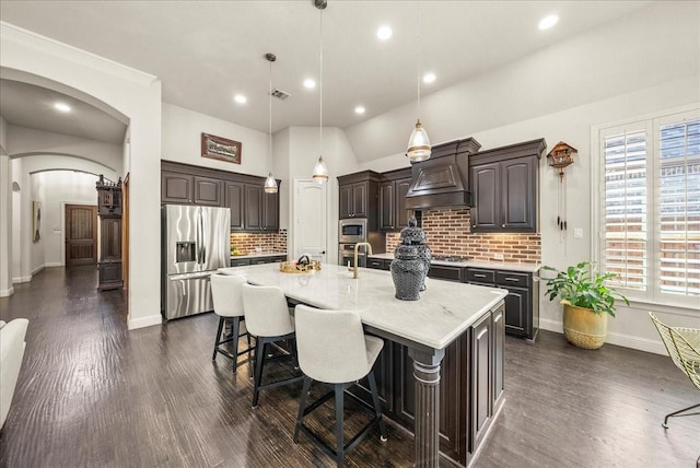 2223 Alisa Ln, Trophy Club, TX 76262 - kitchen featuring stainless steel appliances, dark brown cabinetry, premium range hood, tasteful backsplash, and arched walkways