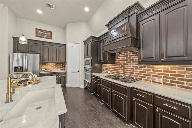 2223 Alisa Ln, Trophy Club, TX 76262 - kitchen with appliances with stainless steel finishes, a sink, dark brown cabinetry, decorative backsplash, and light stone countertops