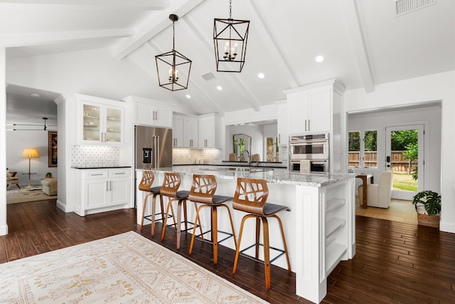 610 Sunset Ct, Argyle, TX 76226 - kitchen featuring stainless steel appliances, white cabinets, dark wood-style floors, backsplash, and a kitchen breakfast bar