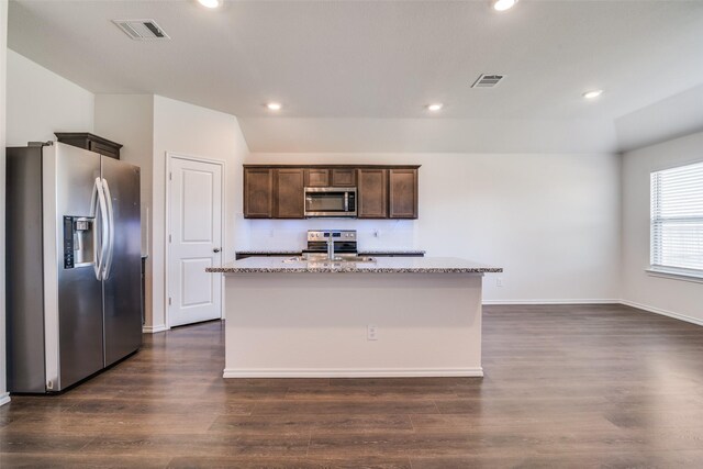 1302 Lowhill Dr, Royse City, TX 75189 - kitchen with appliances with stainless steel finishes, a kitchen island with sink, dark brown cabinets, light stone countertops, and dark wood-style floors