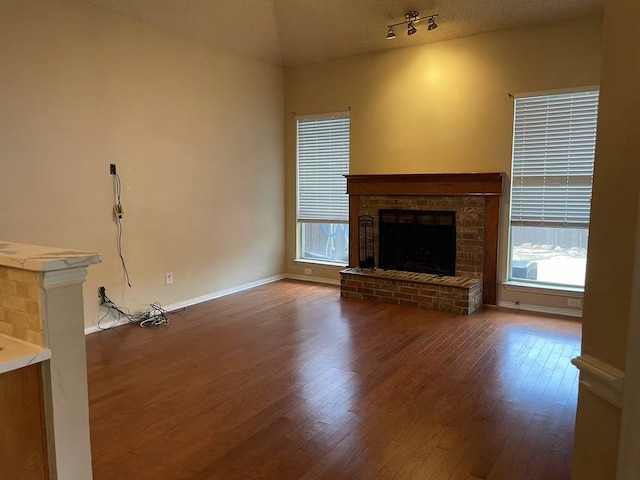 11008 Hermitage Ln, Frisco, TX 75035 - unfurnished living room with wood finished floors, a brick fireplace, and baseboards