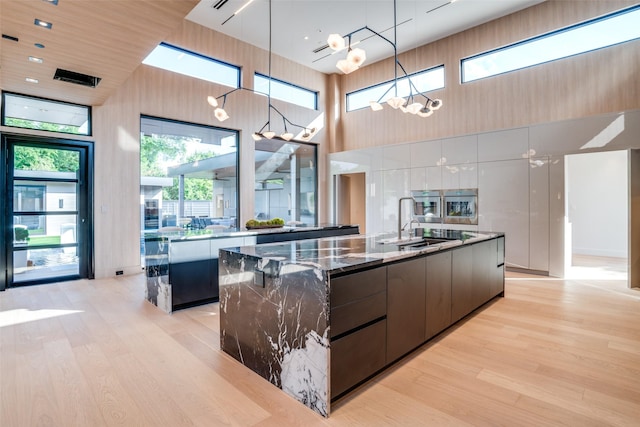 10846 Crooked Creek Ct, Dallas, TX 75229 - kitchen with a large island with sink, modern cabinets, a high ceiling, light wood-style floors, and a sink