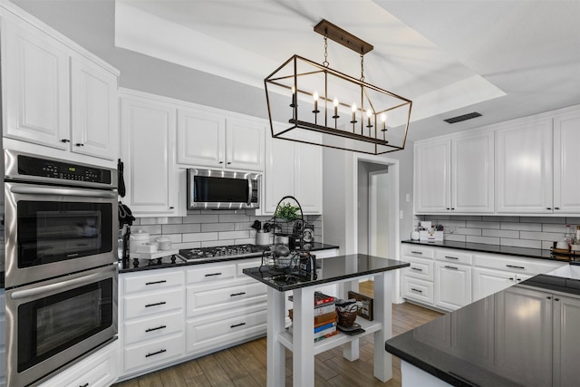 3512 Ridglea Country Club Dr, Fort Worth, TX 76116 - kitchen featuring stainless steel appliances, a tray ceiling, dark countertops, and white cabinetry