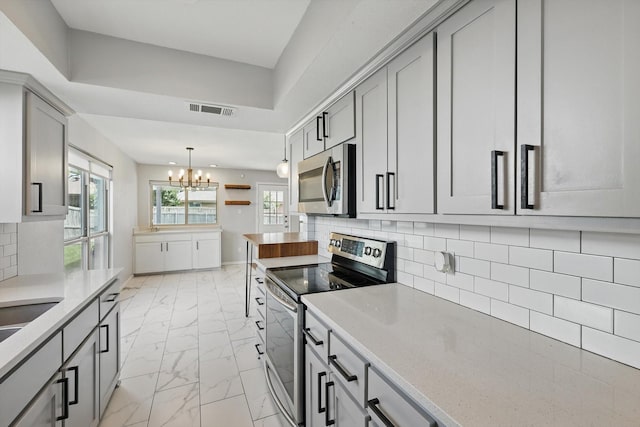 4448 Atlanta Dr, Plano, TX 75093 - kitchen featuring appliances with stainless steel finishes, a chandelier, light marble finish floors, gray cabinetry, and backsplash