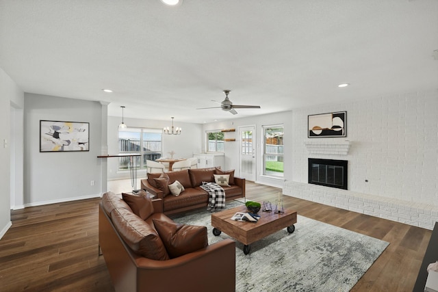 4448 Atlanta Dr, Plano, TX 75093 - living room featuring a brick fireplace, ceiling fan, a chandelier, dark wood-style flooring, and recessed lighting