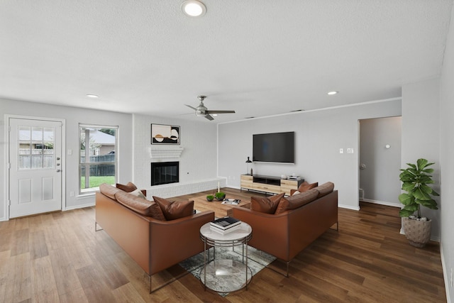 4448 Atlanta Dr, Plano, TX 75093 - living room featuring a ceiling fan, wood finished floors, a brick fireplace, a textured ceiling, and baseboards