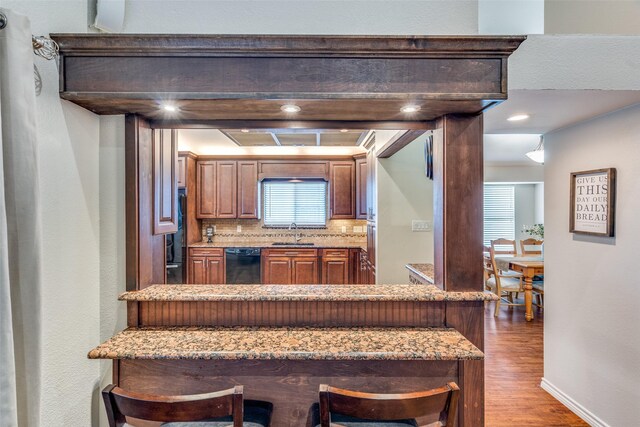 807 Autumn Hill Dr, Wylie, TX 75098 - kitchen featuring black dishwasher, a sink, wood finished floors, a kitchen breakfast bar, and tasteful backsplash