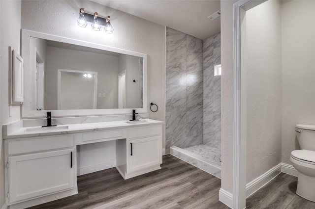 829 Foxridge Dr, Arlington, TX 76017 - full bathroom featuring toilet, double vanity, tiled shower, wood finished floors, and baseboards