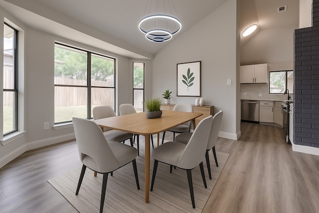 829 Foxridge Dr, Arlington, TX 76017 - dining room featuring light wood-style floors, baseboards, a chandelier, and vaulted ceiling