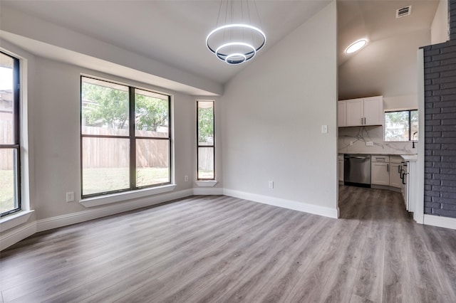829 Foxridge Dr, Arlington, TX 76017 - unfurnished living room with a chandelier, light wood-style floors, plenty of natural light, vaulted ceiling, and baseboards