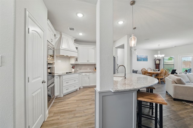 2109 Liriope Ln, Waxahachie, TX 75165 - kitchen featuring a kitchen breakfast bar, custom range hood, light wood-style floors, tasteful backsplash, and white cabinetry