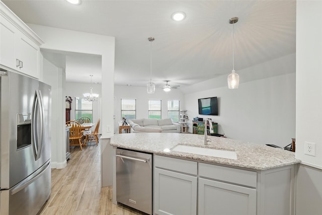 2109 Liriope Ln, Waxahachie, TX 75165 - kitchen featuring appliances with stainless steel finishes, a sink, ceiling fan, a chandelier, and light stone countertops