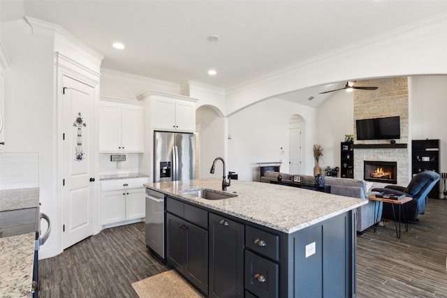 900 E 5th St, Springtown, TX 76082 - kitchen with appliances with stainless steel finishes, a sink, white cabinets, a ceiling fan, and ornamental molding