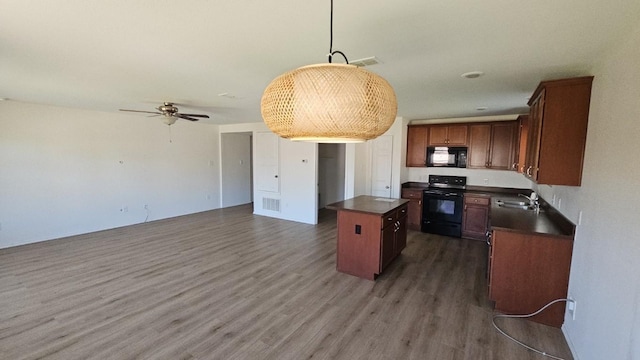 5833 Mirror Ridge Dr, Fort Worth, TX 76179 - kitchen featuring black appliances, dark countertops, a center island, wood finished floors, and a sink