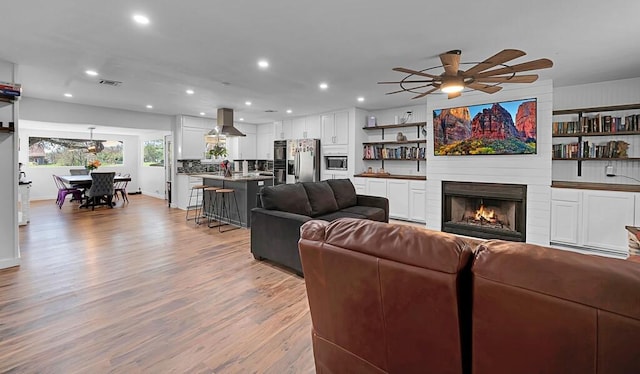 1835 Fort Graham Rd, Waco, TX 76705 - living room featuring light wood-style flooring, ceiling fan, recessed lighting, and a large fireplace