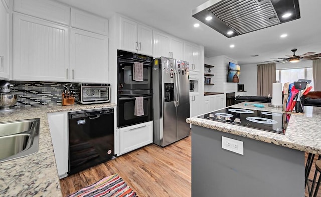 1835 Fort Graham Rd, Waco, TX 76705 - kitchen with black appliances, range hood, light wood-style flooring, tasteful backsplash, and recessed lighting