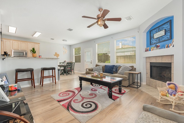 2344 Magnolia Dr, Little Elm, TX 75068 - living area with a ceiling fan, light wood-type flooring, a tiled fireplace, and baseboards