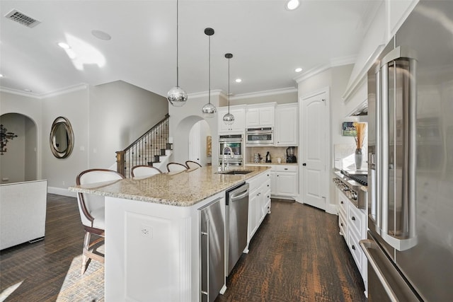 415 Fountainview Dr, Irving, TX 75039 - kitchen with stainless steel appliances, arched walkways, crown molding, a kitchen bar, and white cabinetry