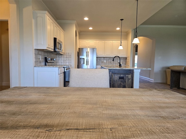 632 Yucca Ct, Aledo, TX 76008 - kitchen featuring appliances with stainless steel finishes, arched walkways, ornamental molding, white cabinetry, and decorative backsplash