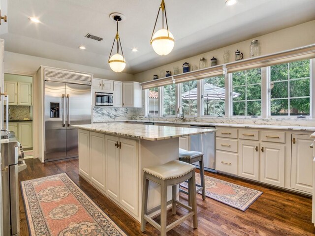 104 Crestwood Dr, Fort Worth, TX 76107 - kitchen with built in appliances, backsplash, a center island, dark wood-type flooring, and light stone countertops