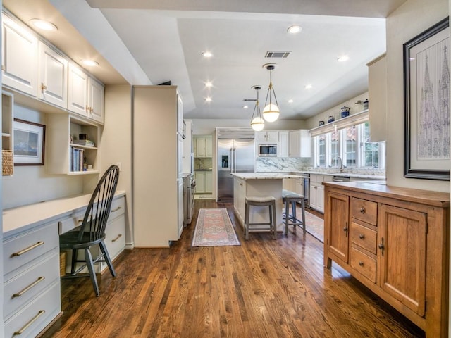 104 Crestwood Dr, Fort Worth, TX 76107 - kitchen with built in appliances, a breakfast bar, a kitchen island, light countertops, and dark wood-type flooring