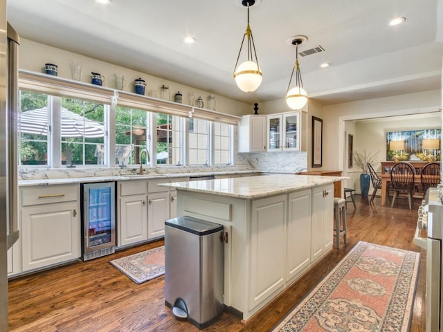 104 Crestwood Dr, Fort Worth, TX 76107 - kitchen featuring wine cooler, a sink, a kitchen island, backsplash, and white cabinets