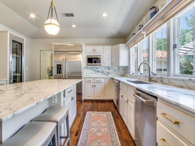 104 Crestwood Dr, Fort Worth, TX 76107 - kitchen with appliances with stainless steel finishes, a sink, dark wood-type flooring, light stone counters, and tasteful backsplash