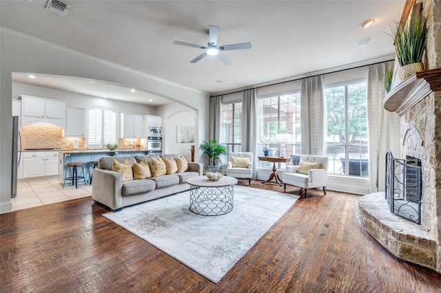 590 Willow Ridge Cir, Prosper, TX 75078 - living room featuring arched walkways, healthy amount of natural light, ceiling fan, a fireplace with raised hearth, and crown molding