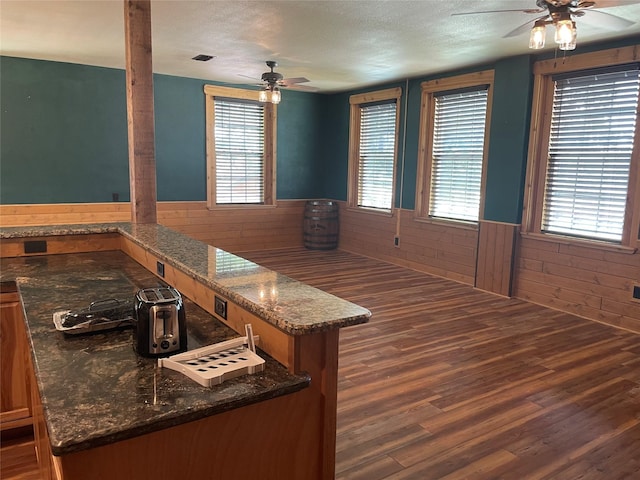 209 E Pine St, Nocona, TX 76255 - dining room featuring a ceiling fan, wainscoting, wood finished floors, a textured ceiling, and wood walls