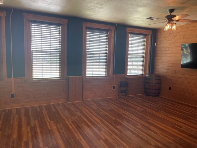 209 E Pine St, Nocona, TX 76255 - spare room featuring a textured ceiling, wood finished floors, a ceiling fan, wainscoting, and wood walls