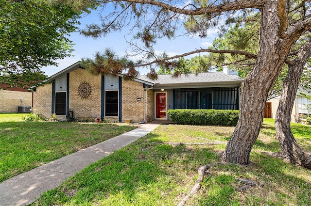 1710 Goliad Dr, Garland, TX 75042 - view of front of house featuring a front lawn, brick siding, a chimney, and central AC