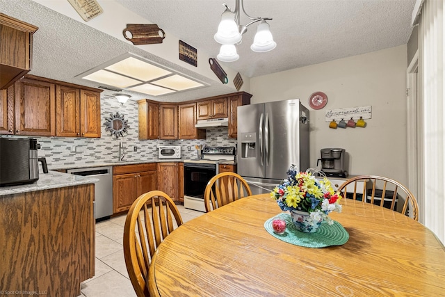 1710 Goliad Dr, Garland, TX 75042 - kitchen featuring stainless steel appliances, under cabinet range hood, a sink, a textured ceiling, and light tile patterned flooring