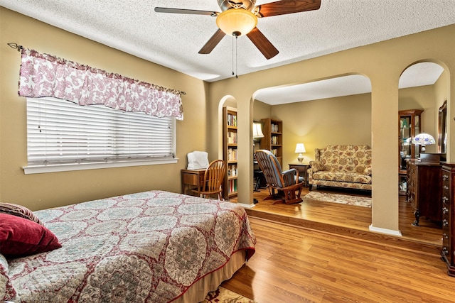 1710 Goliad Dr, Garland, TX 75042 - bedroom with wood finished floors, a textured ceiling, arched walkways, and ceiling fan