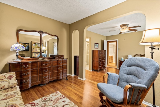 1710 Goliad Dr, Garland, TX 75042 - living area with arched walkways, wood finished floors, a textured ceiling, ceiling fan, and baseboards