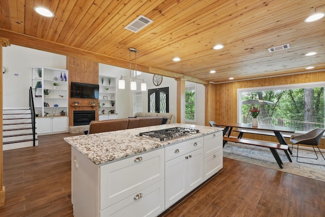 1520 Oakhurst Scenic Dr, Fort Worth, TX 76111 - kitchen featuring stainless steel gas stovetop, wooden ceiling, a kitchen island, light stone counters, and white cabinetry