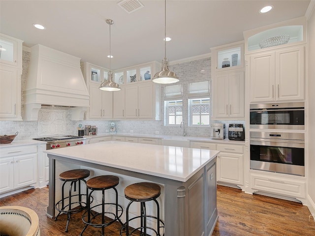 3421 Greenbrier Dr, Frisco, TX 75033 - kitchen with premium range hood, a breakfast bar area, stainless steel appliances, a center island, and white cabinetry
