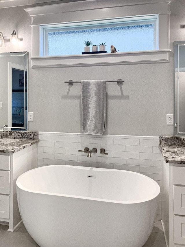 9035 Shallow Cv, Tyler, TX 75703 - full bath featuring tile walls, two vanities, a freestanding tub, plenty of natural light, and wainscoting